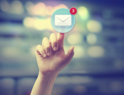 Hand pressing an email icon on blurred cityscape background