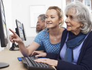 Tutor Helping Senior Woman In Computer Class