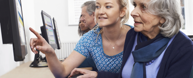 Tutor Helping Senior Woman In Computer Class